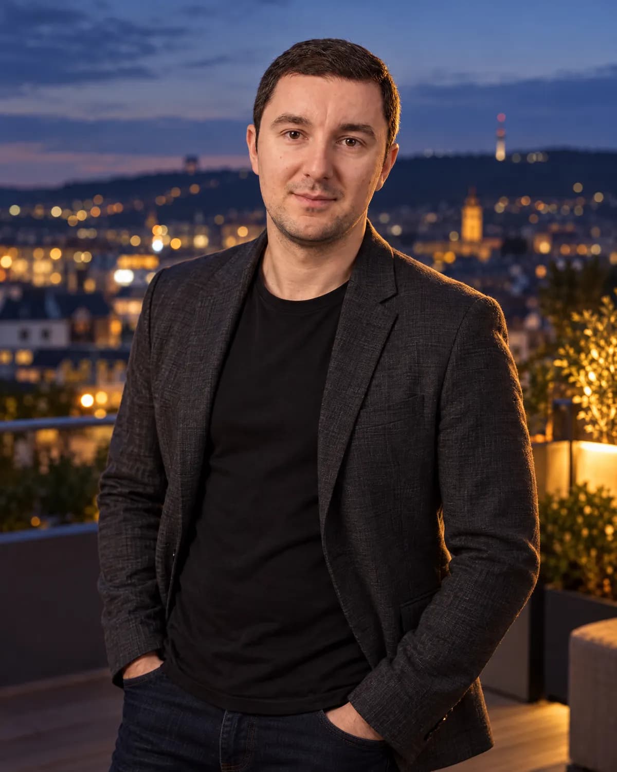 Michael Zogot auf einer Dachterrasse, dahinter Stuttgart am Abend