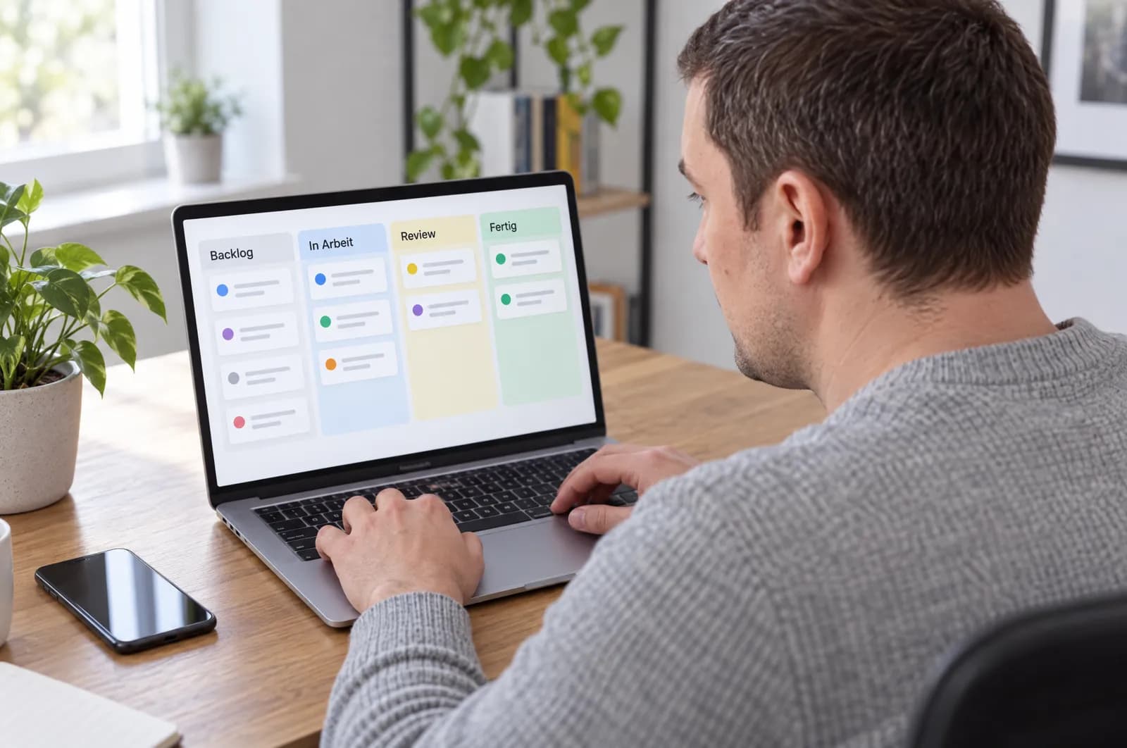 Michael Zogot am MacBook Pro, auf dem Bildschirm ein Kanban-Board