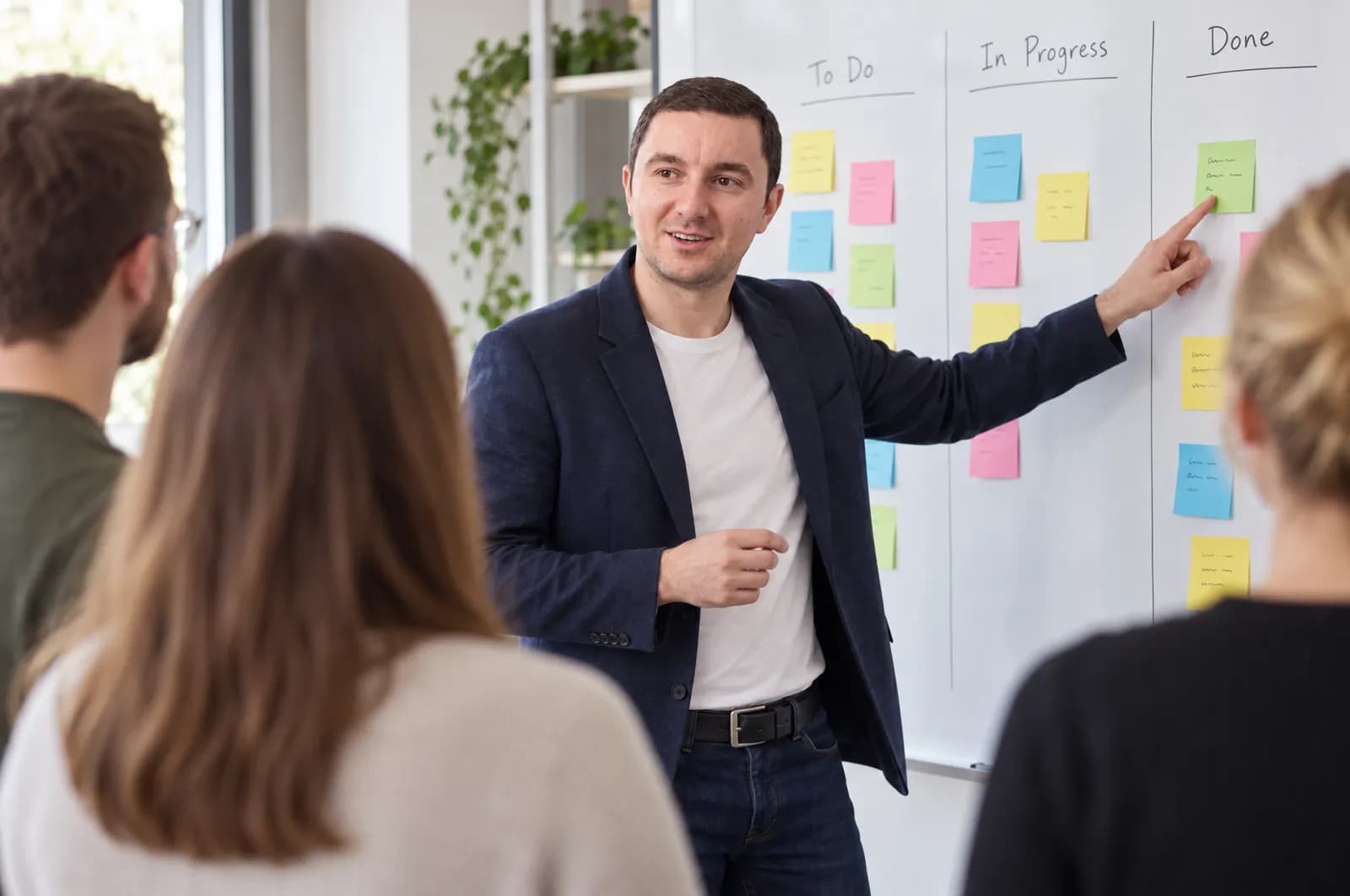 Michael Zogot leitet ein Stand-up vor einem Kanban-Board mit Haftnotizen